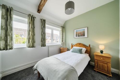 a bedroom with a bed and two windows at Bettys Barn in Evershot
