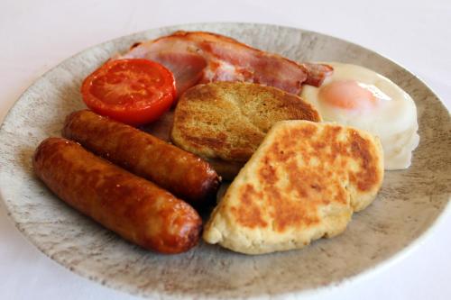 un plato de desayuno con huevos, salchichas y tomates en Carnalbanagh House, en Portstewart