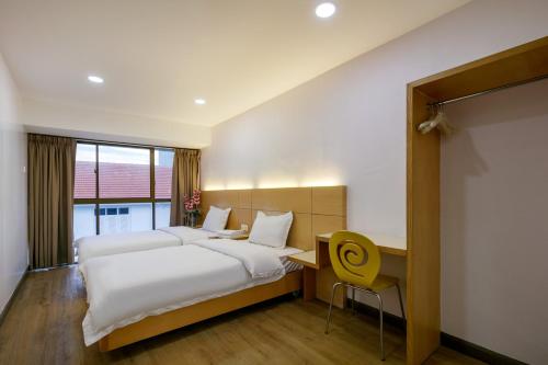 a hotel room with two beds and a desk and a window at Gaia Realty Homestay, Private & Convenient Stay in Georgetown in George Town