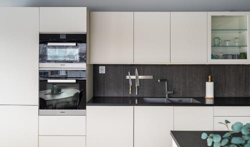a kitchen with white cabinets and a sink at North Estate City House in Tromsø