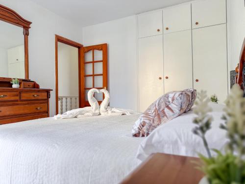 a bedroom with a bed with white sheets and a dresser at El Delfín in Playa de las Americas