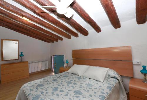 a bedroom with a bed and a mirror and wooden ceilings at Casa rural La Siasa in Hoz de Barbastro