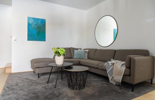 a living room with a couch and a round mirror at North Estate City House in Tromsø