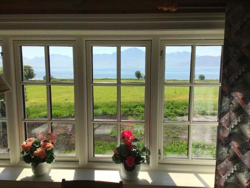 a window with three vases with flowers on a table at Gamlemgarden by Norgesbooking - house by the sea in Longva