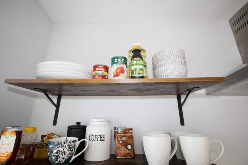 a shelf in a kitchen with dishes and cups at Granbury Loft - 1 Bedroom in Granbury