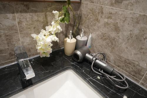 ein Waschbecken mit einem Haartrockner und Blumen darauf in der Unterkunft R&F Seine Region Victoria Style 3Bedroom in Johor Bahru