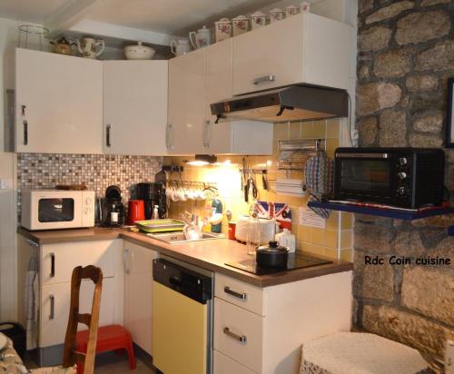 a small kitchen with white cabinets and a microwave at PentyTy TadKozh Très proche du port de Kérity in Penmarcʼh
