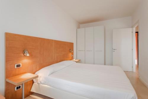 a bedroom with a white bed and a wooden headboard at Allegroitalia Elba Golf in Portoferraio