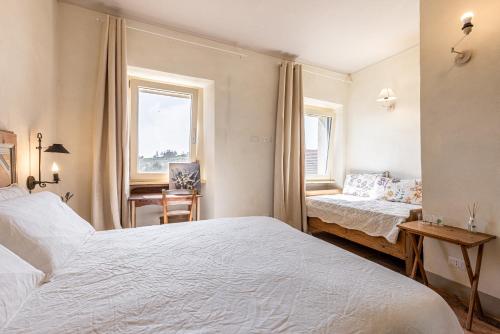 a bedroom with two beds and a desk and a window at Le libellule relais in San Lorenzo