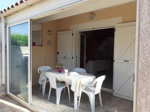 une salle à manger avec une table et des chaises blanches dans l'établissement Villa proche de la plage, à Port-la-Nouvelle