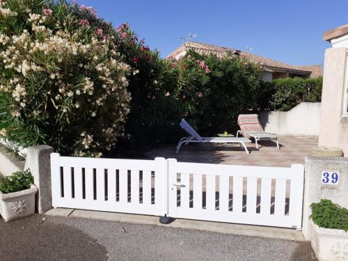 une clôture blanche avec deux chaises et une table dans l'établissement Villa proche de la plage, à Port-la-Nouvelle