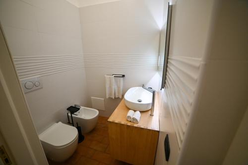 a white bathroom with a toilet and a sink at Agriturismo Il Poeta Contadino in Merine