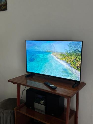 a flat screen tv on a wooden stand with a remote control at Vikendica S, Alibegovac in Petrovaradin