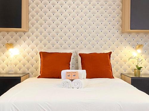 une chambre avec un grand lit blanc avec des oreillers orange dans l'établissement GuestReady - Warm and Stylish Nest in the 13th, à Paris