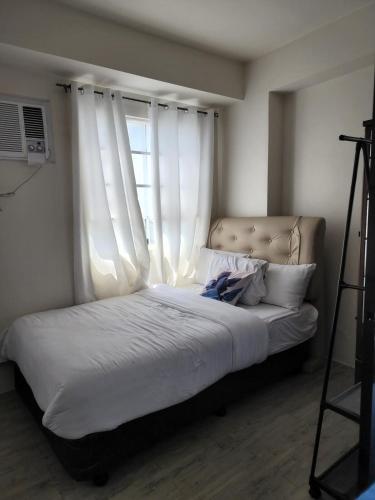 a bed with white curtains in a bedroom at Capitol Central Condo, 2 Bedroom in Bacolod