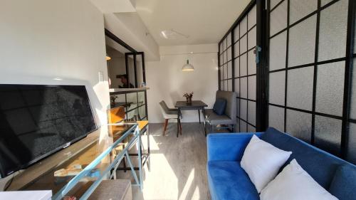 a living room with a blue couch and a tv at Capitol Central Condo, 2 Bedroom in Bacolod