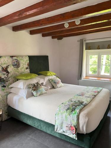 une chambre avec un grand lit avec des draps et des oreillers blancs dans l'établissement Relais Du Destin, à Vertrieu