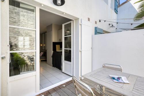 Une porte ouverte s'ouvre sur une terrasse avec une table. dans l'établissement 335 Mérindot 5 Au coeur du village, à Saint-Martin-de-Ré