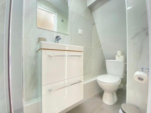 une salle de bain blanche avec des toilettes et un lavabo dans l'établissement GuestReady - Cozy nest in Salpêtrière, à Paris