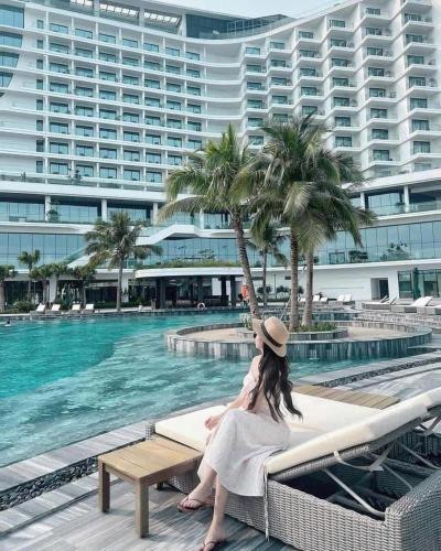 a woman sitting on a bench next to a swimming pool at Anna Belle Đồi Rồng Hotel - Homestay chuỗi HPT Home Hải Phòng in Kon Rung (1)