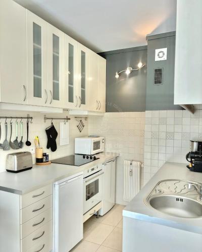 une cuisine blanche avec un évier et un micro-ondes dans l'établissement Le Petit Hermitage, à Le Touquet-Paris-Plage