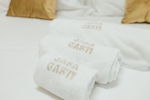 a pile of white towels with the words cast east on a bed at B&B Casa Casti in Margherita di Savoia