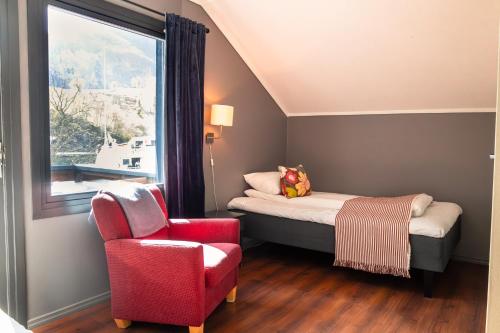 a bedroom with a bed and a chair and a window at Flåmsbrygga Hotel in Flåm