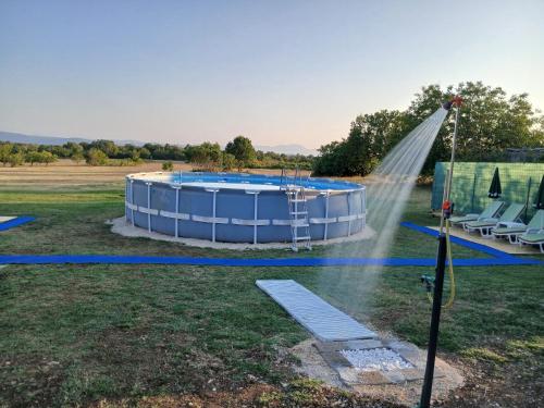 a pool with a water sprinkler in a field at Zavičajna kuća Šakota - Kozice in Stolac