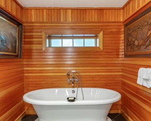 a white bath tub in a room with wooden walls at Mill Falls Resort Collection at the Lake in Meredith