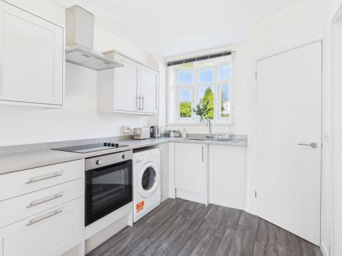 a white kitchen with white cabinets and a dishwasher at Modern 3 bed Willenhall house in Willenhall