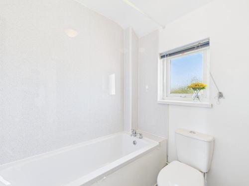 a white bathroom with a tub and a toilet and a window at Modern 3 bed Willenhall house in Willenhall