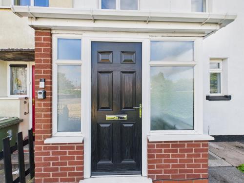 a black door on a brick house with windows at Modern 3 bed Willenhall house in Willenhall
