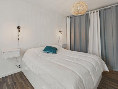 une chambre avec un lit blanc avec un oreiller bleu dans l'établissement Jolie maison avec jardin et terrasse pour 4, à Fouesnant