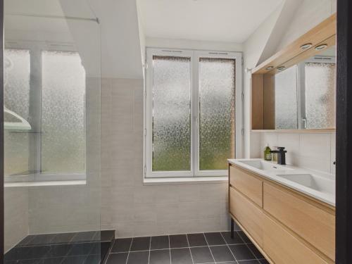 La salle de bains est pourvue d'un lavabo, d'une baignoire et de fenêtres. dans l'établissement Jolie maison avec jardin et terrasse pour 4, à Fouesnant