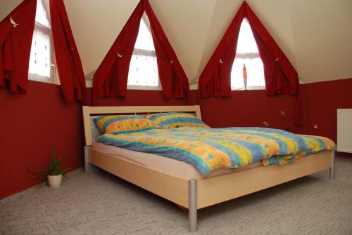 a bedroom with a bed with red walls and windows at Iso Apartman Siófok in Siófok