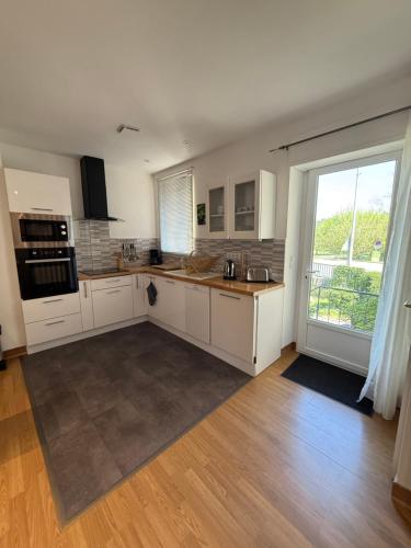 une cuisine avec des placards blancs et une grande fenêtre dans l'établissement Maison de Ville, à Montignac