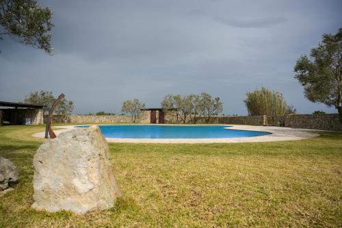 a large rock sitting in the grass next to a pool at Agriturismo Il Poeta Contadino in Merine