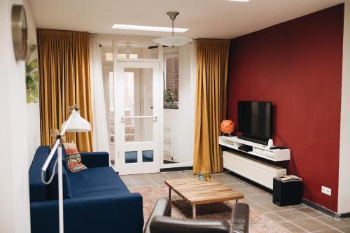 a living room with a blue couch and a tv at Independent Basement Apartment in Nijmegen