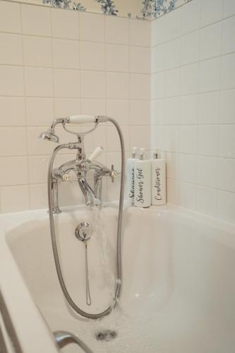 a bath tub with a shower in a bathroom at Claggan Farmhouse, Loch Tay in Aberfeldy
