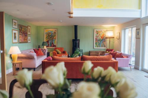 a living room with couches and tables and flowers at Claggan Farmhouse, Loch Tay in Aberfeldy