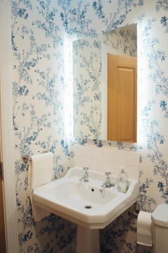 a bathroom with a sink and blue floral wallpaper at Claggan Farmhouse, Loch Tay in Aberfeldy