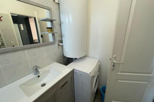une salle de bain blanche avec un lavabo et un miroir dans l'établissement Escale Baheux, au Havre