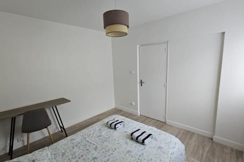 Cette chambre blanche comprend un lit et un bureau. dans l'établissement Appartement spacieux F5 au Havre, au Havre