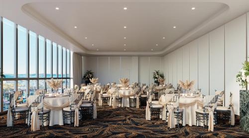 a banquet hall with white tables and chairs and large windows at voco Gosford by IHG in Gosford