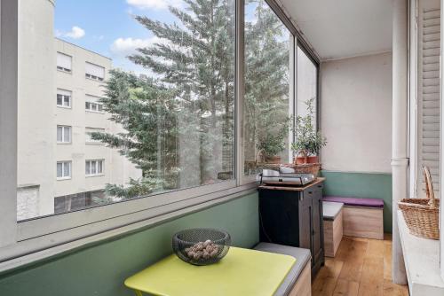 Cette chambre dispose d'une grande fenêtre et d'une table jaune. dans l'établissement Magnifique appartement au cœur du 6ème, à Lyon