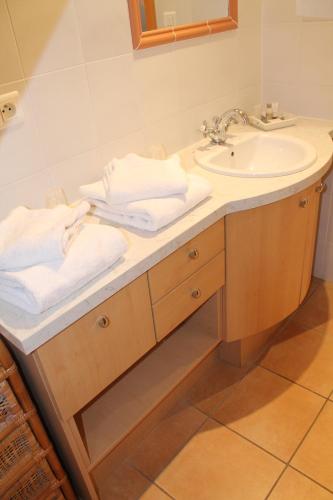 a bathroom with a sink and a mirror and towels at Maison d'Hôtes Sainte Hune Chambres et appartements in Hunawihr