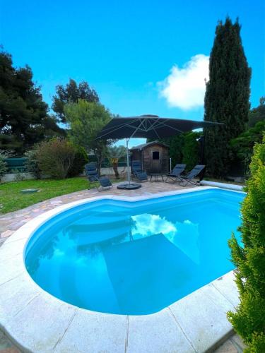 - une piscine avec un parasol et des chaises dans l'établissement VILLA CONSTANCE - Swimming pool & Parking - sleeps 8, à Six-Fours-les-Plages