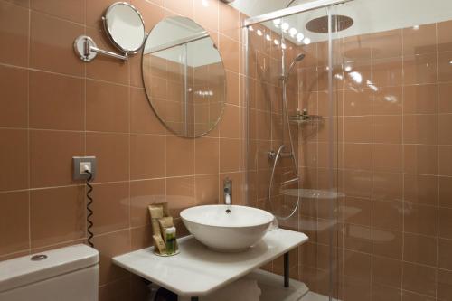 a bathroom with a sink and a shower with a mirror at Petit Palace Puerta de Triana in Seville