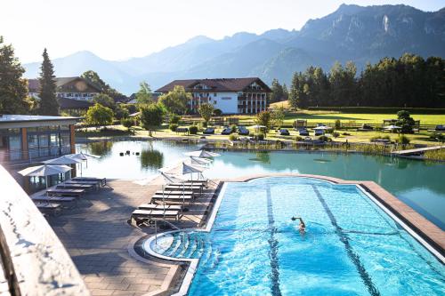 a person in a swimming pool with mountains in the background at Das König Ludwig Inspiration SPA in Schwangau