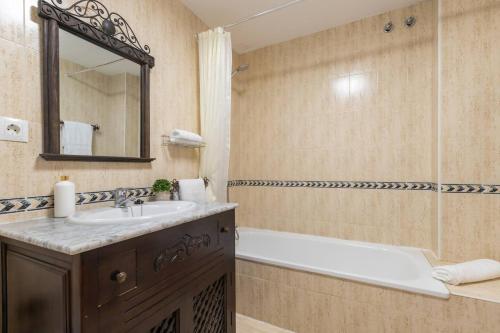 Un baño con bañera, lavabo y espejo. en Apartamento Playa Vistamar, en Estepona
